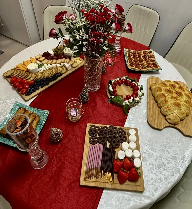 Christmas party table styled by Ghanjani Jain, seen from above: red runner, roses, candles and sharing platters